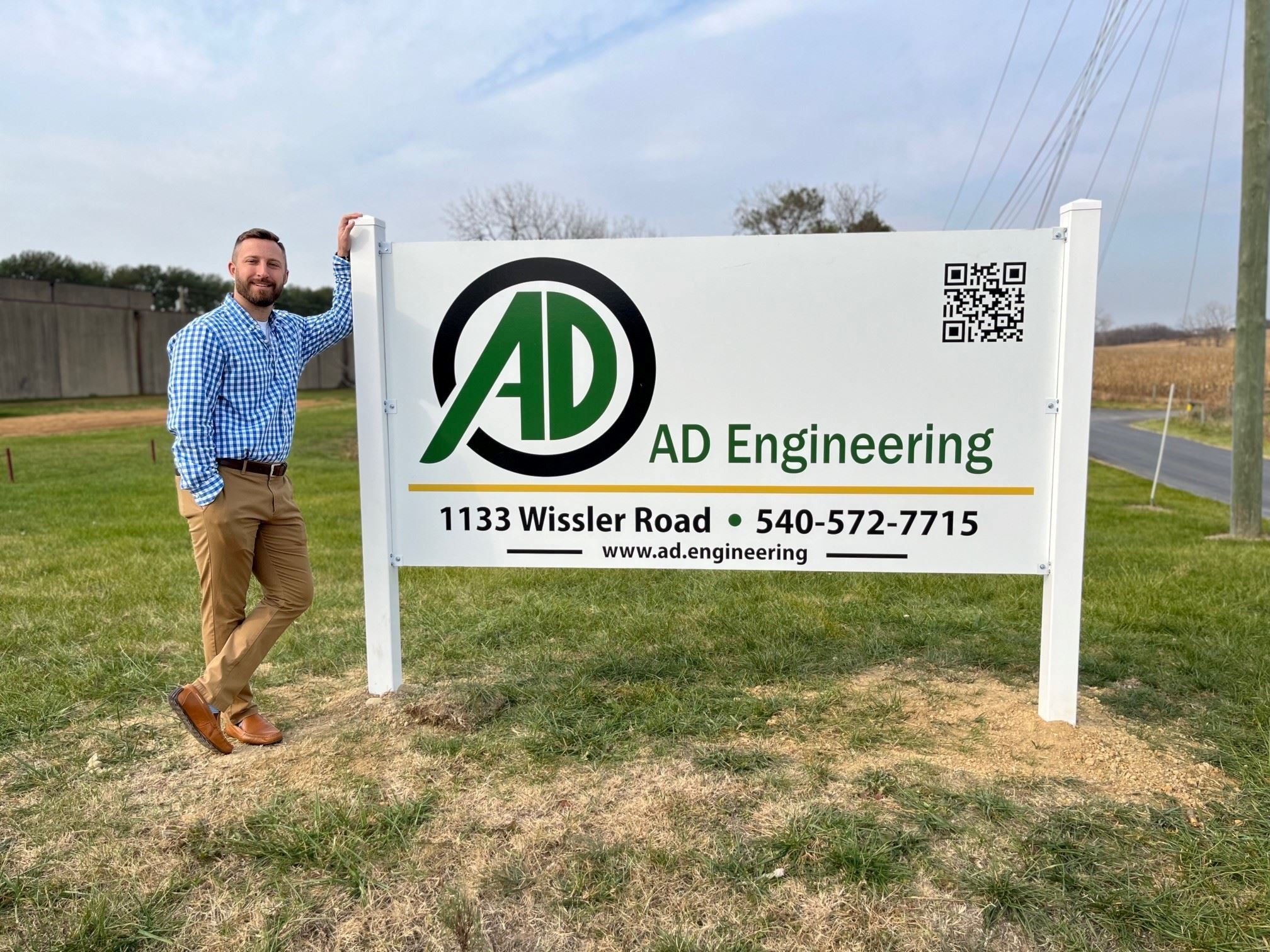 Blake With AD Engineering Standing Next to their Business Sign